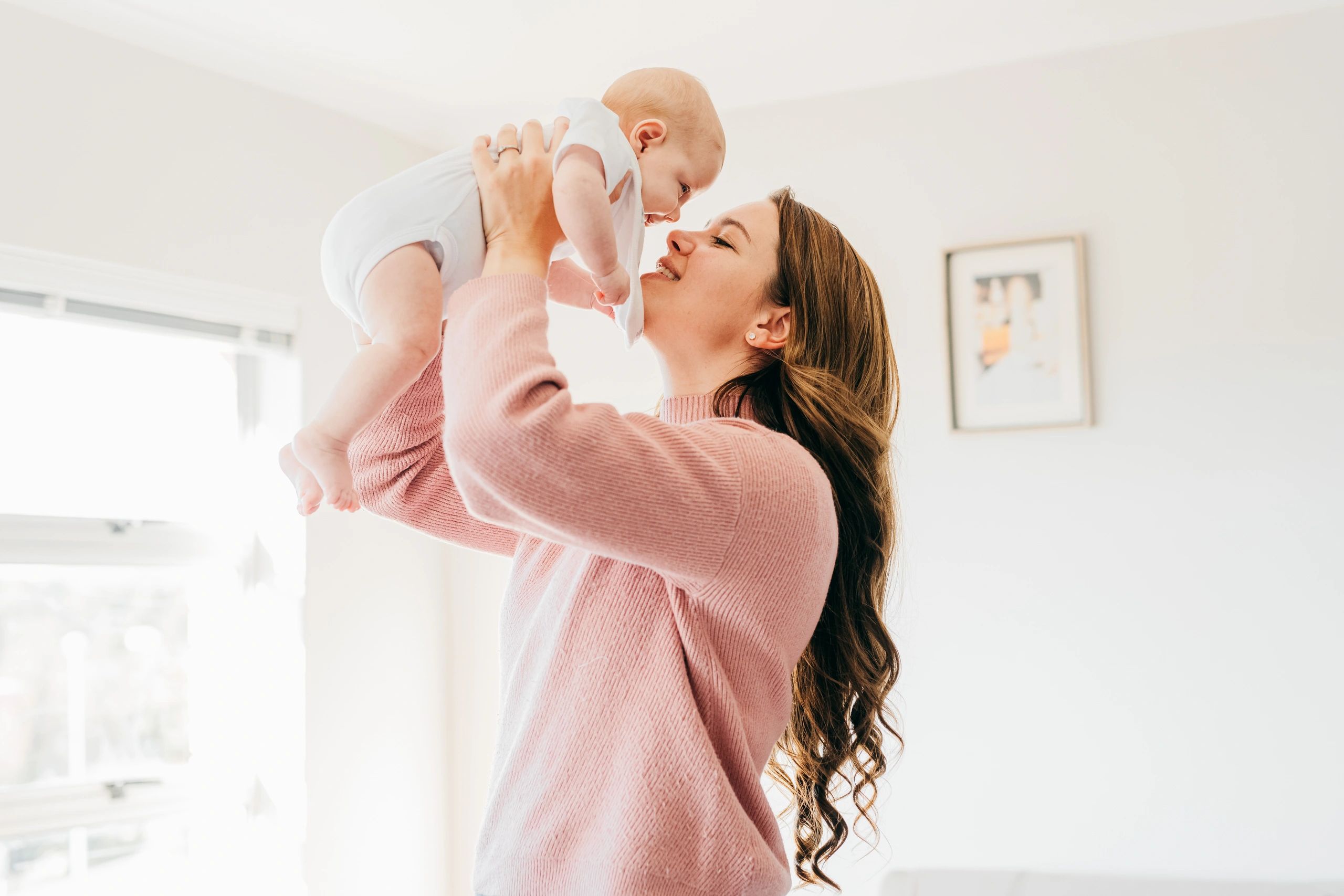 Portrait-style image of a smiling mother holding her baby